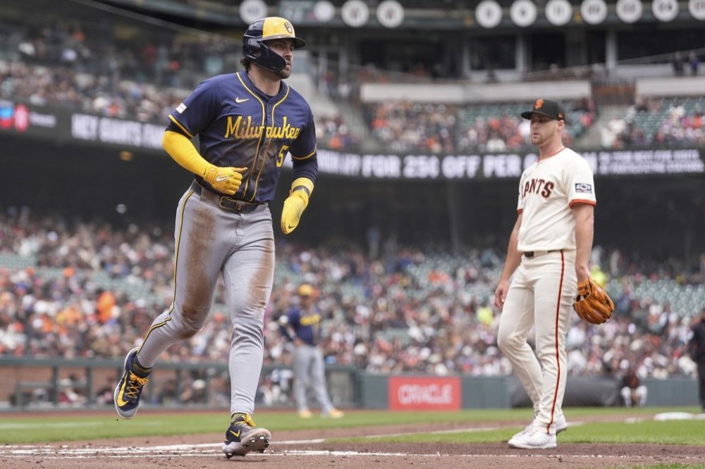 Milwaukee Brewers' Garrett Mitchell (5) scores after a wild pitch by San Francisco Giants pitcher Landen Roupp, right, during the second inning of a baseball game in San Francisco, Thursday, April 24, 2025. (AP Photo/Jeff Chiu)