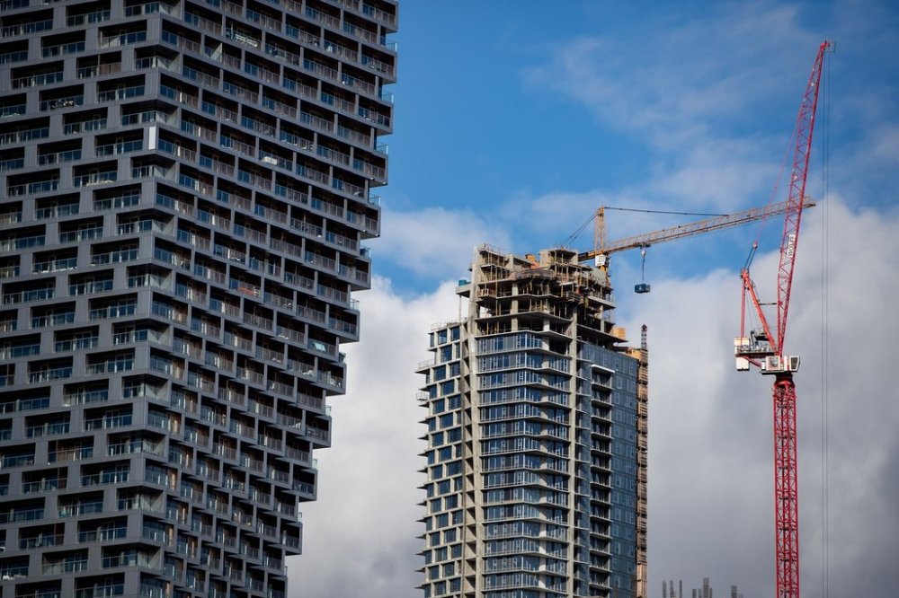 A crane is used to move a garbage bin to the upper floors of a condo tower under construction in Vancouver on February 16, 2021. THE CANADIAN PRESS/Darryl Dyck