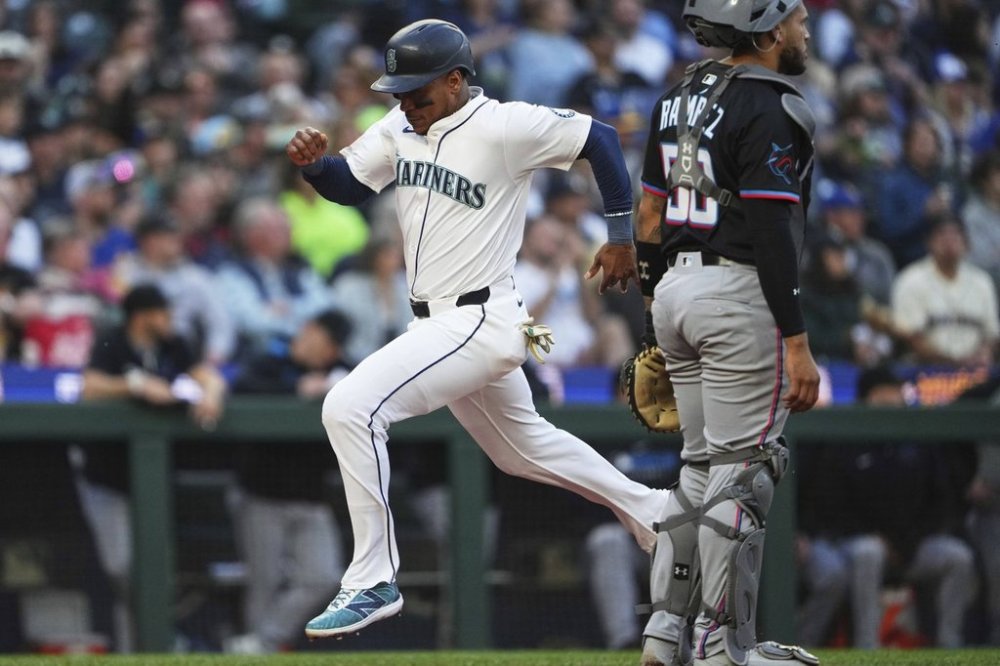 Seattle Mariners' Jorge Polanco scores on a sacrifice fly by Luke Raley as Miami Marlins catcher Agustín Ramírez looks to the outfield during the second inning of a baseball game Saturday, April 26, 2025, in Seattle. (AP Photo/Lindsey Wasson)