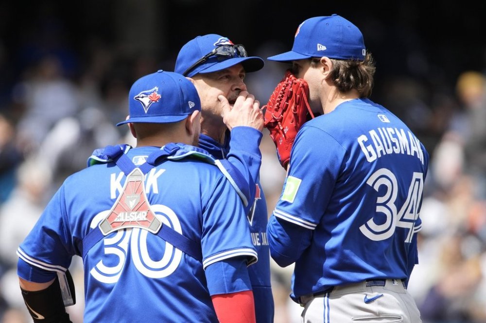Toronto Blue Jays catcher Alejandro Kirk, left, and pitcher Kevin Gausman, right, talk to pitching coach Pete Walker, center, during the third inning of the first baseball game of a doubleheader against the New York Yankees, Sunday, April 27, 2025, in New York. (AP Photo/Pamela Smith)