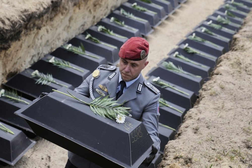 with the remains of fallen German soldiers of WWII to the grave during a funeral service at a memorial site for fallen soldiers in Halbe, Germany, Wednesday, April 30, 2025. (AP Photo/Ebrahim Noroozi)