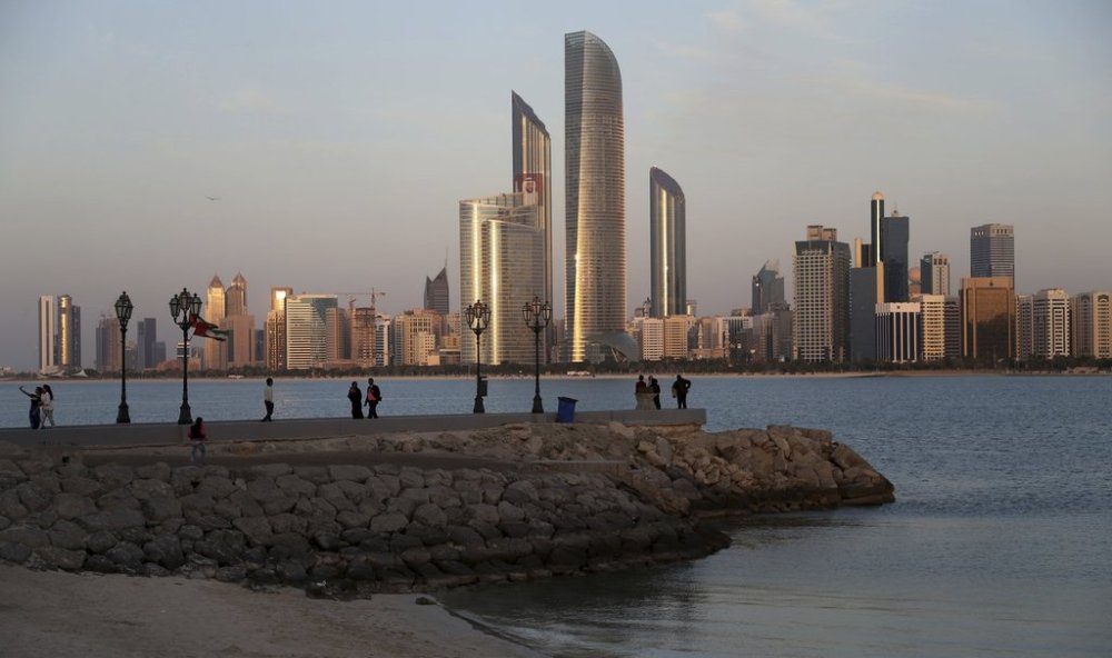 FILE - With the city skyline in backdrop, people of different nationalities enjoy a good weather of 24 degrees Celsius (75.2 degrees Fahrenheit) n Abu Dhabi, United Arab Emirates, Wednesday, Jan. 14, 2015. (AP Photo/Kamran Jebreili, File)