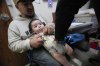 Cesar Acevedo, left, holds his infant son, Adriel Acevedo, as as nurse Tracey McElroy, right, prepares to give him a vaccination that included a polio dose at the Dallas County Health and Human Services immunization clinic in Dallas, Friday, April 4, 2025. (AP Photo/LM Otero)