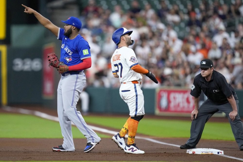 Toronto Blue Jays first baseman Vladimir Guerrero Jr., left, points to left fielder Alan Roden after Guerrero Jr. completed a double play off Houston Astros' Jose Altuve, centre, during the first inning of a baseball game Monday, April 21, 2025, in Houston. (AP Photo/Eric Christian Smith)