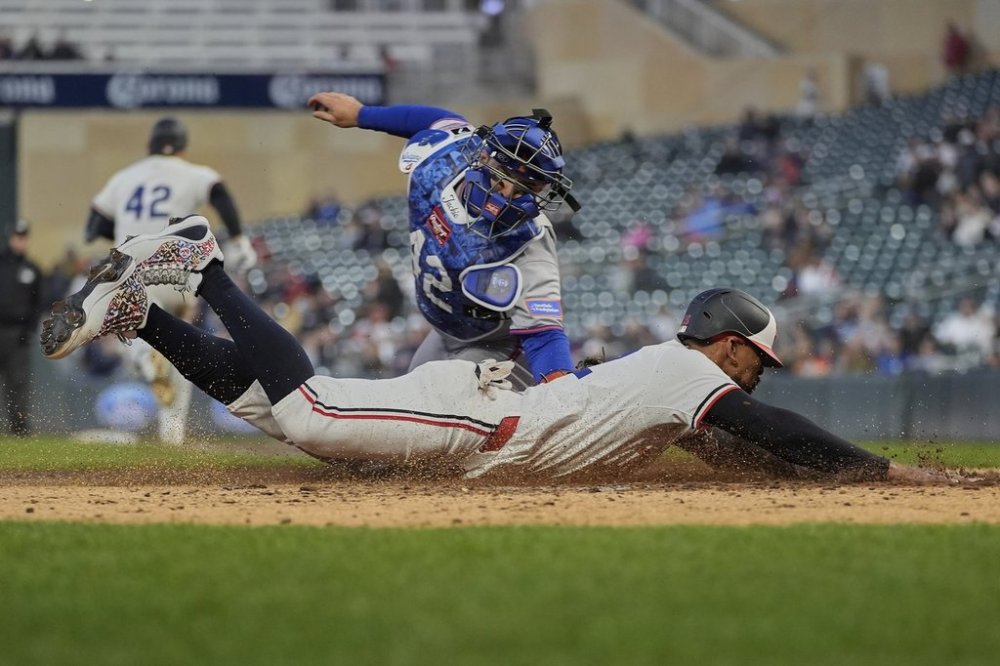 Minnesota Twins' Byron Buxton beats the tag by New York Mets catcher Luis Torrens (13) to score during the fifth inning of a baseball game Tuesday, April 15, 2025, in Minneapolis. (AP Photo/Abbie Parr)