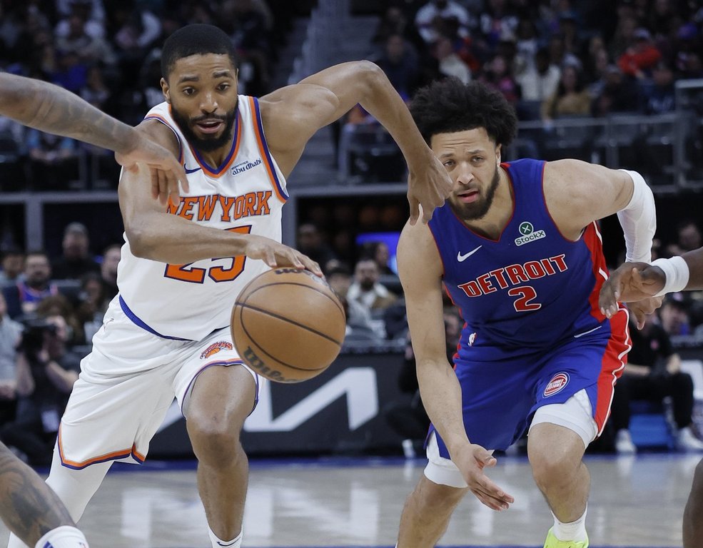 New York Knicks forward Mikal Bridges, left, drives the lane past Detroit Pistons guard Cade Cunningham (2) during the first half of an NBA basketball game Thursday, April 10, 2025, in Detroit. (AP Photo/Duane Burleson)