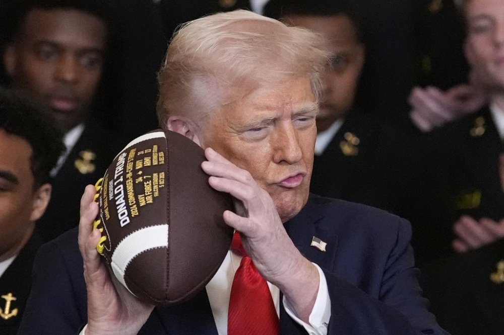 President Donald Trump holds a football during the Commander-in-Chief trophy presentation to the Navy Midshipman football team in the East Room of the White House, Tuesday, April 15, 2025, in Washington. (AP Photo/Alex Brandon)