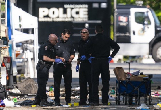 Members of the Vancouver Police forensics team examine a victim's phone while investigating the scene where a vehicle drove into crowd at a street festival Saturday evening in Vancouver, Sunday, April 27, 2025. THE CANADIAN PRESS/Rich Lam