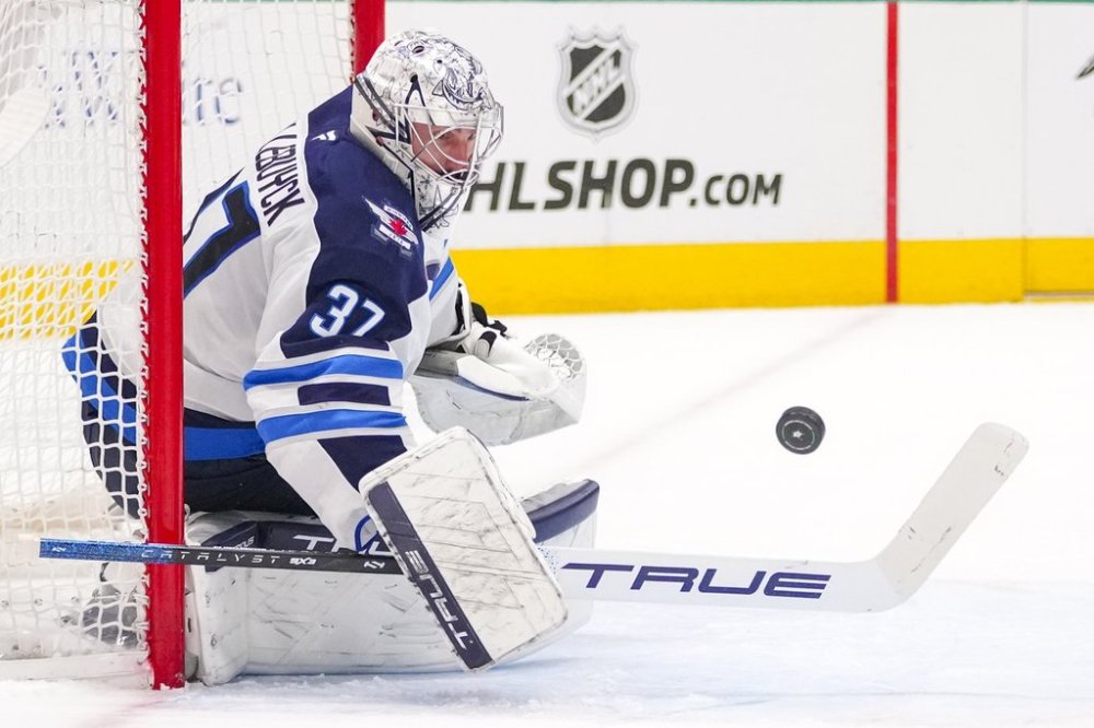Winnipeg Jets goaltender Connor Hellebuyck blocks a shot by the Dallas Stars during the first period of an NHL hockey game Thursday, April 10, 2025, in Dallas. (AP Photo/Julio Cortez)