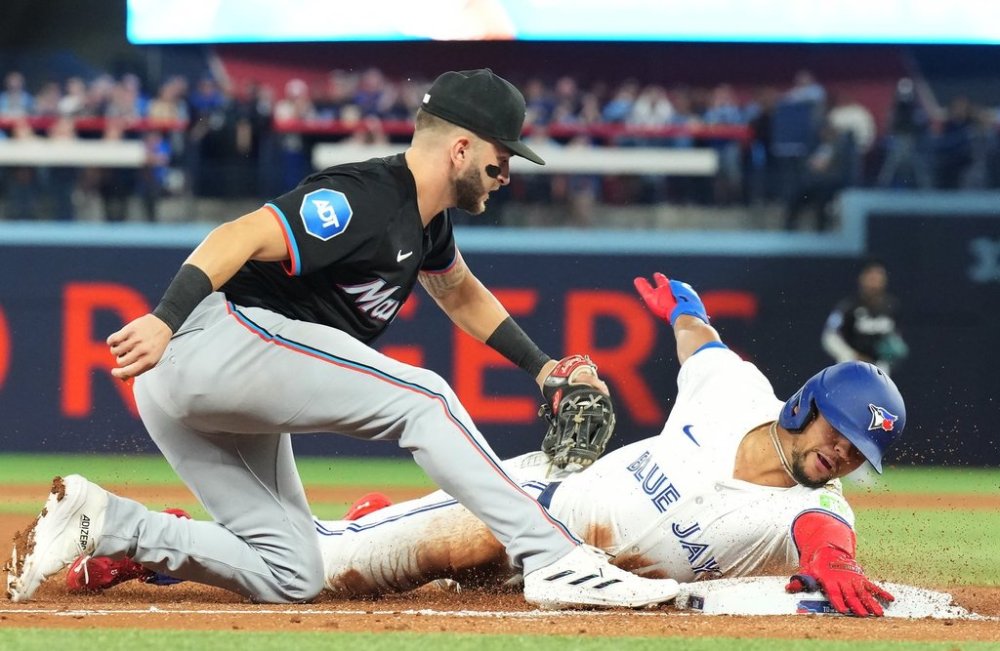 Toronto Blue Jays' Jonatan Clase (right) is tagged out at third base by Miami Marlins third baseman Connor Norby (24) during second inning interleague MLB baseball action in Toronto, Friday, September 27, 2024. THE CANADIAN PRESS/Chris Young