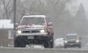 A motorist negotiates a wet roadway on South Colorado Boulevard as a pair of storms packing high winds, freezing temperatures and snow sweep over the intermountain West Friday, April 18, 2025, in Denver. (AP Photo/David Zalubowski)