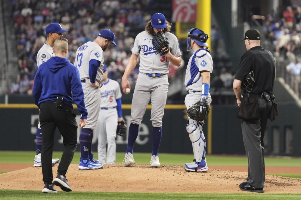 Los Angeles Dodgers infielders, umpire Nic Lentz, right, and a team staff member check on starting pitcher Tyler Glasnow, who left the game with an unknown injury, in the fifth inning of a baseball game against the Texas Rangers in Arlington, Texas, Sunday, April 20, 2025. (AP Photo/Tony Gutierrez)