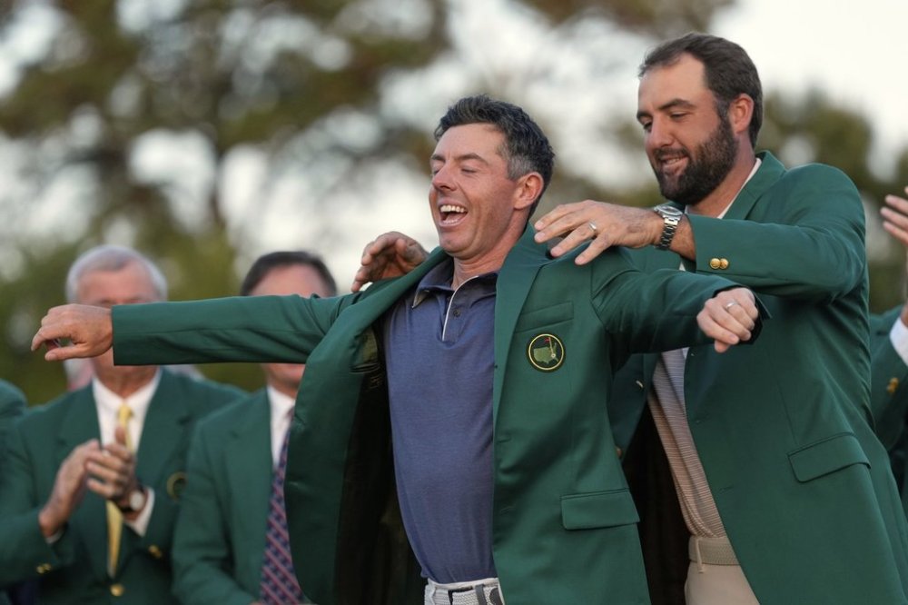 Scottie Scheffler puts the green Jacket on winner, Rory McIlroy, of Northern Ireland, at the Masters golf tournament, Sunday, April 13, 2025, in Augusta, Ga. (AP Photo/Ashley Landis)