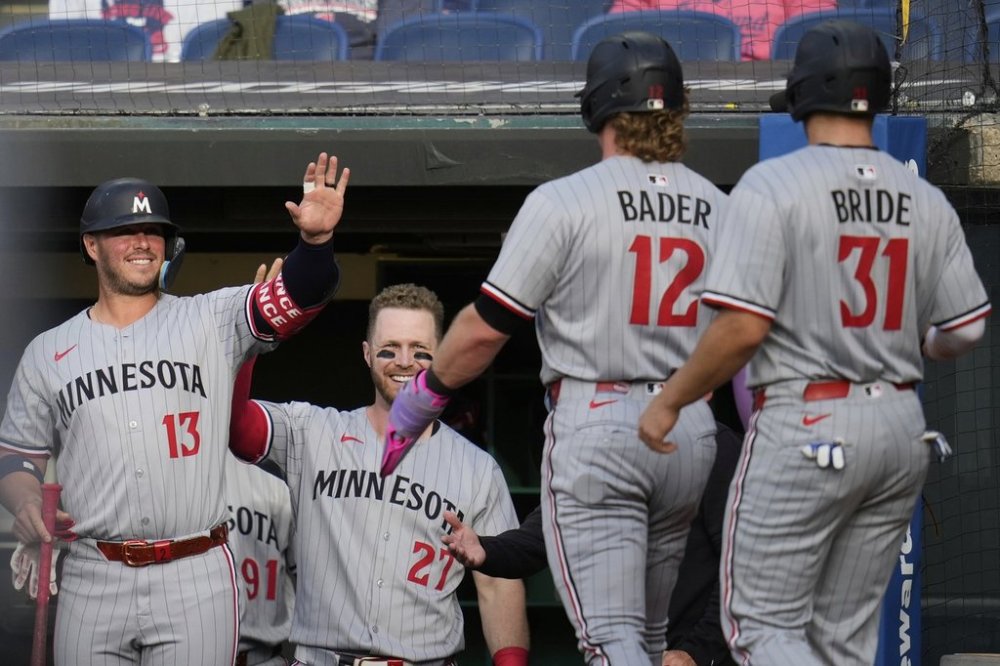 Minnesota Twins' Harrison Bader (12) and Jonah Bride (31) are greeted by teammates Ty France (13) and Ryan Jeffers (27) as they return to the dugout after scoring on a single hit by Byron Buxton in the second inning of a baseball game against the Cleveland Guardians in Cleveland, Monday, April 28, 2025. (AP Photo/Sue Ogrocki)
