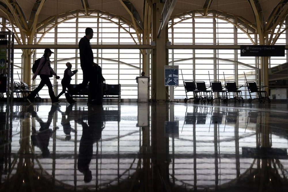 FILE - Travelers walk along a concourse at Reagan National Airport on July 19, 2024, in Arlington, Va. (AP Photo/Mark Schiefelbein, file)