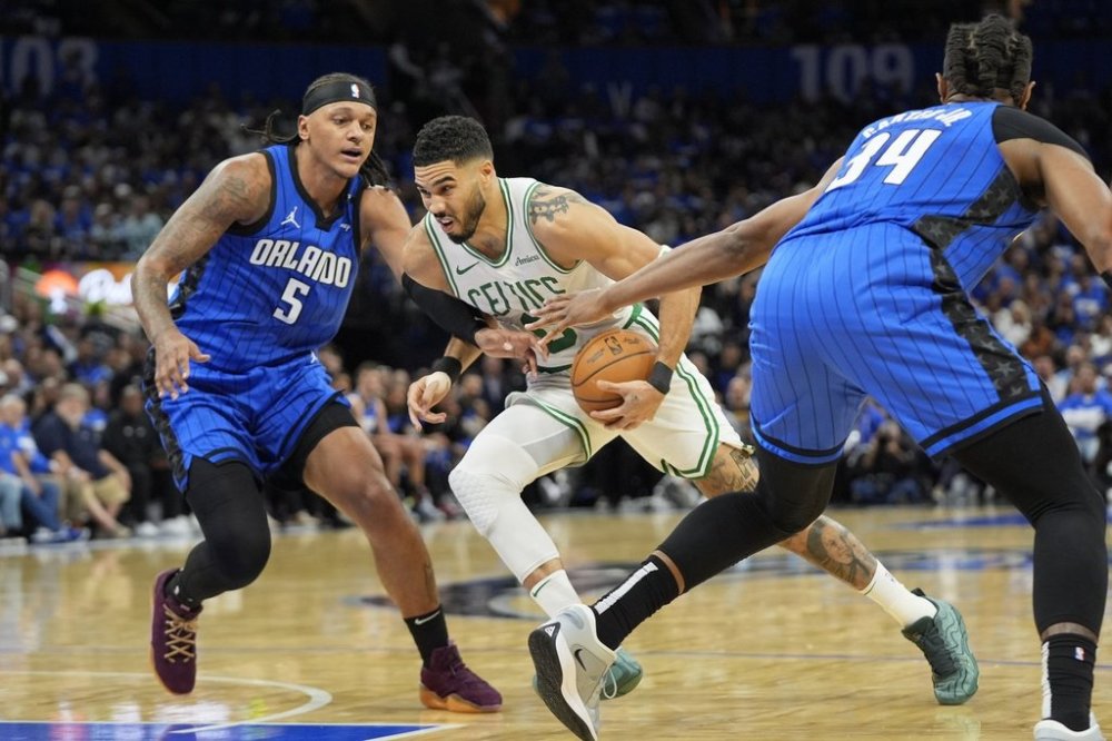 Boston Celtics forward Jayson Tatum, center, drives between Orlando Magic forward Paolo Banchero (5) and center Wendell Carter Jr. (34) during the first half in Game 4 of a first-round NBA basketball playoff series, Sunday, April 27, 2025, in Orlando, Fla. (AP Photo/John Raoux)