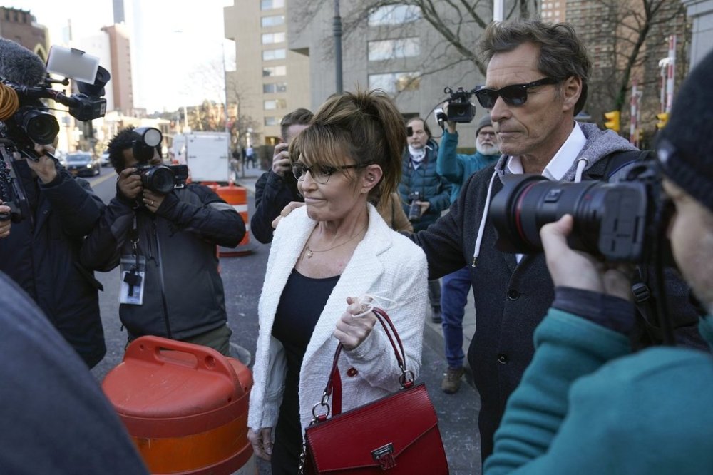FILE - Former Alaska Gov. Sarah Palin is escorted to her car by Ron Duguay after leaving the courthouse in New York, Thursday, Feb. 10, 2022, after she told a jury she felt like she was at the mercy of a