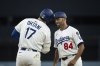 Los Angeles Dodgers' Shohei Ohtani (17) bumps his head with first base coach/infield coach Chris Woodward (84) after hitting a single during the first inning of a baseball game against the Colorado Rockies in Los Angeles, Monday, April 14, 2025. (AP Photo/Kyusung Gong)