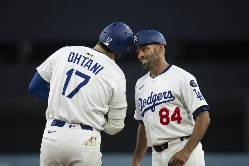 Los Angeles Dodgers' Shohei Ohtani (17) bumps his head with first base coach/infield coach Chris Woodward (84) after hitting a single during the first inning of a baseball game against the Colorado Rockies in Los Angeles, Monday, April 14, 2025. (AP Photo/Kyusung Gong)