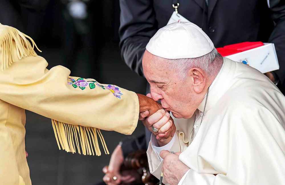 Pope Francis kisses the hand of residential school survivor Elder Alma Desjarlais of the Frog Lake First Nation as he arrives in Edmonton, Alberta, Canada, on Sunday, July 24, 2022. THE CANADIAN PRESS/Nathan Denette