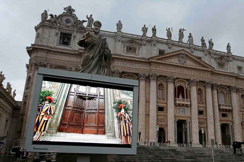 FILE - A giant monitor in St. Peter's Square at the Vatican, Tuesday, March 12, 2013 shows the heavy wooden door to the Sistine Chapel being closed and locked, signaling the start of the conclave to elect a new pope to succeed Benedict XVI following his stunning resignation. (AP Photo/Gregorio Borgia, File)
