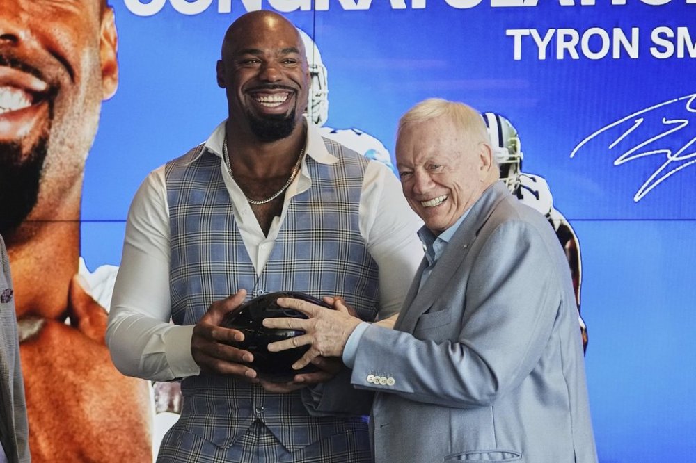 Football player Tyron Smith, left, laughs as he and Dallas Cowboys team owner Jerry jones, right, hold a gift that was presented to Smith by the team after a news conference where Smith announced his retirement from the NFL at the Cowboys headquarters in Frisco, Texas, Wednesday, April 16, 2025. (AP Photo/Tony Gutierrez)