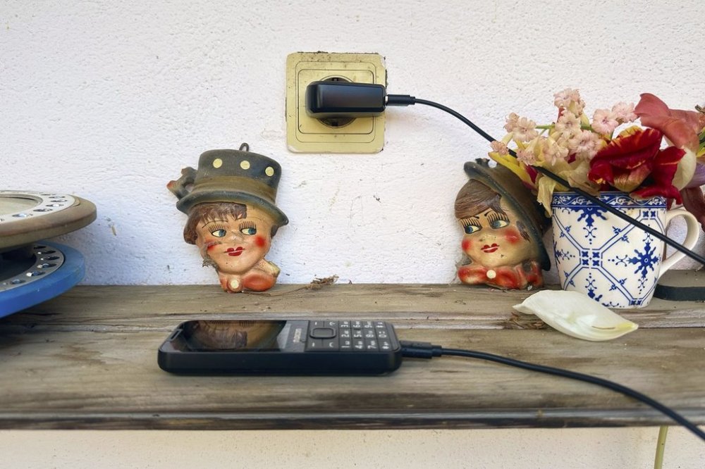 A mobil phone is charging outdoors at the home Zoica Roth, 83, in the village of Saschiz, in Romania's central Transylvania region, Friday, April 25, 2025. (AP Photo/Stephen McGrath)