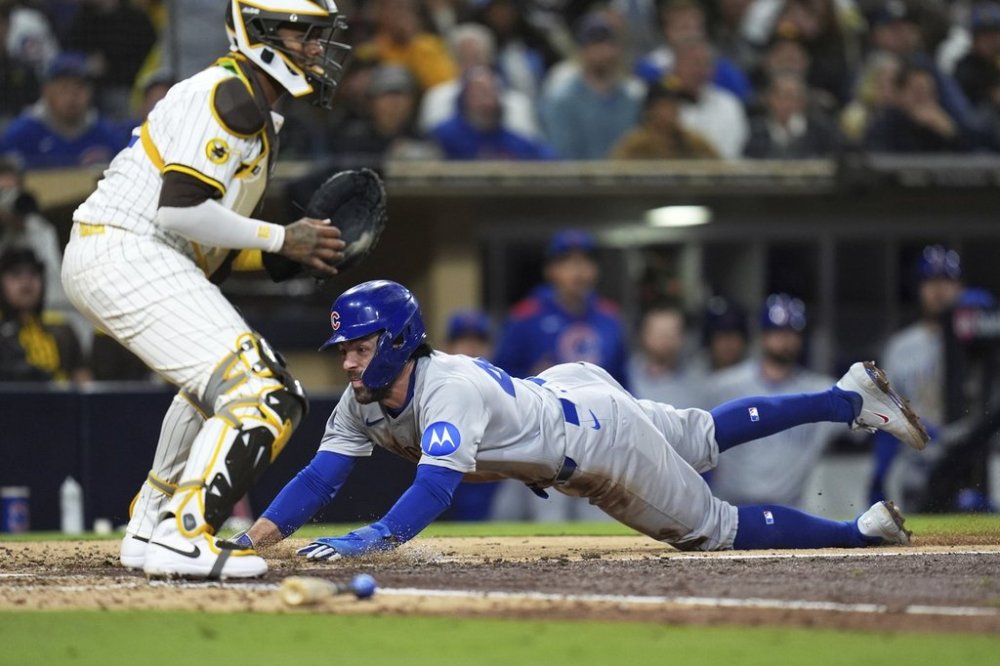 Chicago Cubs' Dansby Swanson, right, slides in to score off a sacrifice bunt by Pete Crow-Armstrong as San Diego Padres catcher Martin Maldonado waits for the throw during the sixth inning of a baseball game Tuesday, April 15, 2025, in San Diego. (AP Photo/Gregory Bull)