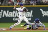 Texas Rangers shortstop Corey Seager, left, throws to first base on a fielder's choice as Los Angeles Dodgers' Eddie Rosario, right, is out at second base during the third inning of a baseball game Saturday, April 19, 2025, in Arlington, Texas. (AP Photo/Jeffrey McWhorter)