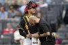 Pittsburgh Pirates catcher Endy Rodríguez, top, is checked by a trainer, bottom, after getting injured during the first inning of a baseball game against the Washington Nationals, Monday, April 14, 2025, in Pittsburgh. (AP Photo/Matt Freed)