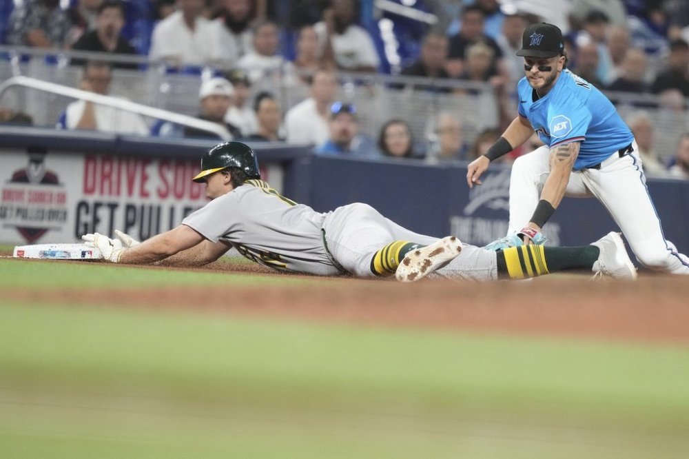 Oakland Athletics' Nick Kurtz, left, beats the throw to Miami Marlins third baseman Connor Norby, right, for a triple during the ninth inning of a baseball game, Sunday, May 4, 2025, in Miami. (AP Photo/Lynne Sladky)