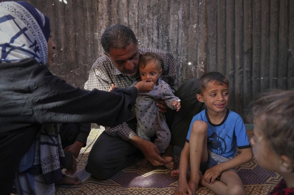 Wedad Abdelaal and her husband Ammar , feed their 9 month old son Khaled, in their tent at a camp for displaced Palestinians in Mawasi Khan Younis, Gaza Strip, Friday, May 2, 2025. (AP Photo/Abdel Kareem Hana)