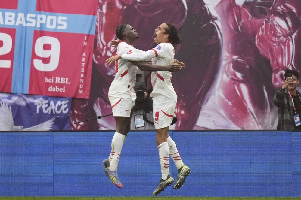 Leipzig's Yussuf Poulsen, right, celebrates with Ridle Baku after scoring his side's third goal during the German Bundesliga soccer match between RB Leipzig and FC Bayern Munich at the Red Bull Arena in Leipzig, Germany, Saturday, May 3, 2025. (AP Photo/Matthias Schrader)