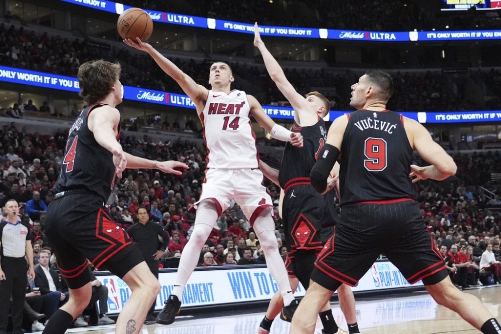 Miami Heat guard Tyler Herro (14) drives to the basket against Chicago Bulls forward Matas Buzelis, left, guard Kevin Huerter and center Nikola Vucevic, right, during the first half of an NBA play-in tournament basketball game in Chicago, Wednesday, April 16, 2025. (AP Photo/Nam Y. Huh)