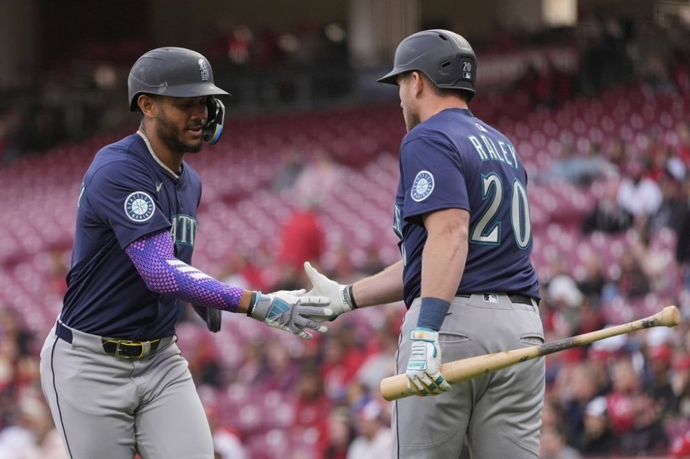 Seattle Mariners' Julio Rodríguez, left, celebrates with Seattle Mariners Luke Raley, right, after scoring on a double hit by Randy Arozarena in the first inning of a baseball game against the Cincinnati Reds, Wednesday, April 16, 2025, in Cincinnati. (AP Photo/Carolyn Kaster)