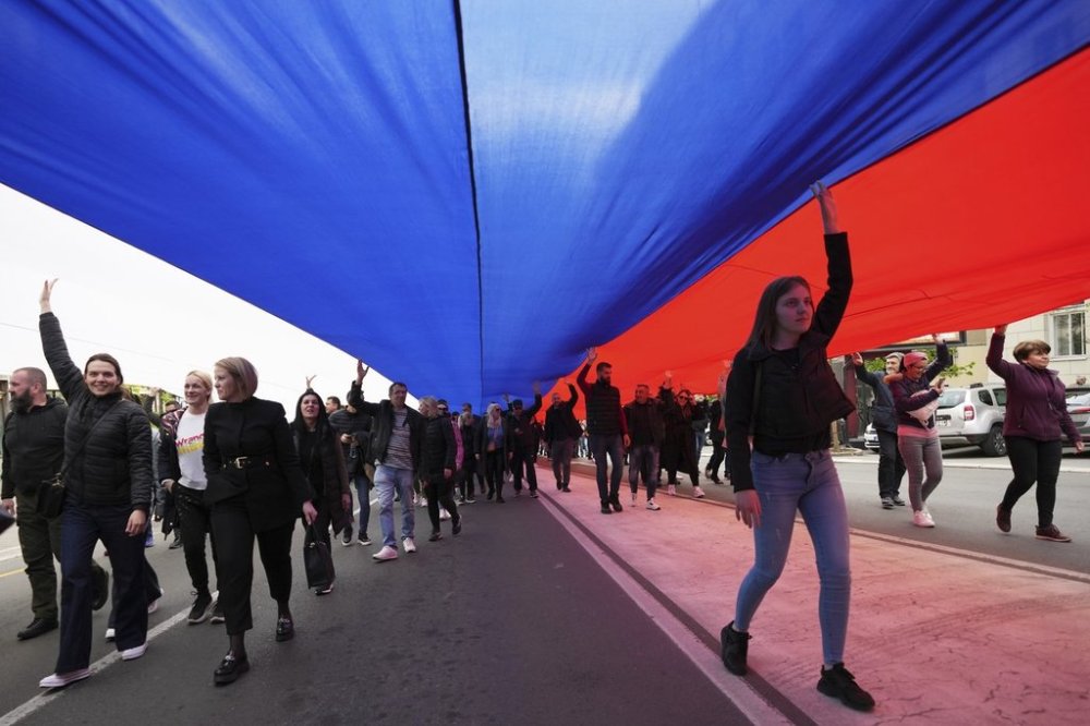 People hold a giant Serbian flag ahead of a big counter-opposition protest rally planned to stage over the weekend in downtown Belgrade, Serbia, Friday, April 11, 2025. (AP Photo/Darko Vojinovic)