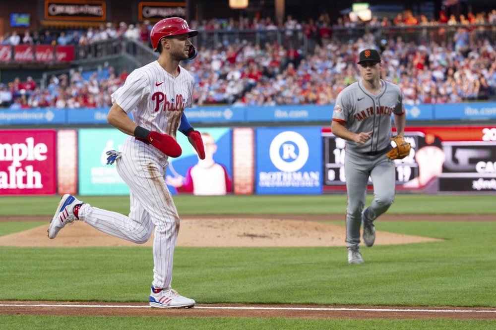 Philadelphia Phillies' Trea Turner, left, comes in to score as San Francisco Giants starting pitcher Landen Roupp, right, looks on during the first inning of a baseball game, Monday, April 14, 2025, in Philadelphia. (AP Photo/Chris Szagola)