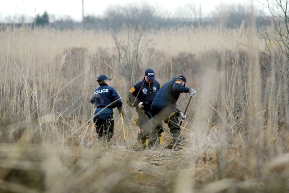 FILE - Crime scene investigators use metal detectors to search a marsh for the remains of a victim, Dec. 12, 2011 in Oak Beach, N.Y. (James Carbone/Newsday via AP, Pool, File)