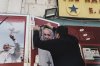 A shop owner places a black ribbon over a photo of the late Pope Francis after the news of his death at age 88, in Bethlehem, West Bank, on Monday, April 21, 2025. (AP Photo/Mahmoud Illean)