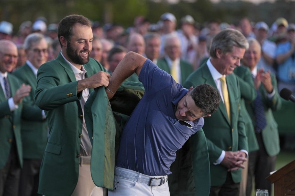 Scottie Scheffler puts the green Jacket on winner, Rory McIlroy, of Northern Ireland, at the Masters golf tournament, Sunday, April 13, 2025, in Augusta, Ga. (AP Photo/Matt Slocum)