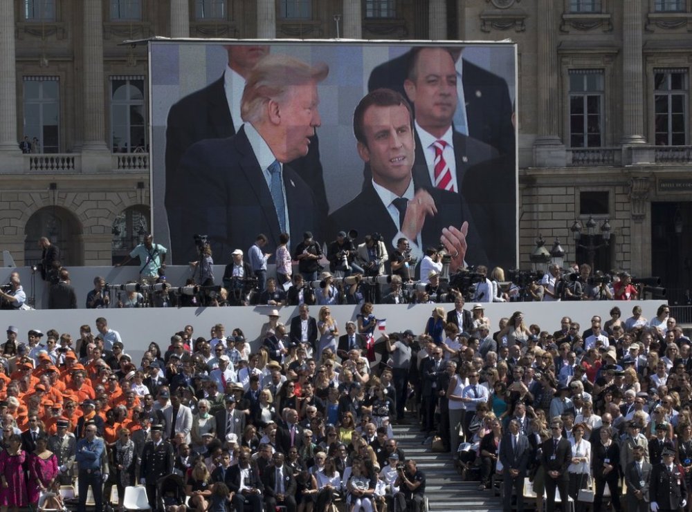 FILE - President Donald Trump, pictured on screen from left, French President Emmanuel Macron and White House Chief of Staff Reince Priebus watch a Bastille Day parade on the Champs Elysees avenue in Paris, July 14, 2017. (AP Photo/Carolyn Kaster, File)