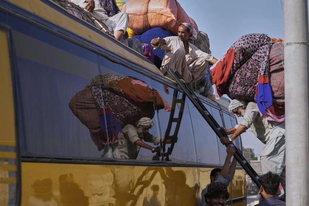 A laborer loads belongings of Afghan refugees onto the roof of a bus as the refugees prepare to return to Afghanistan, at a terminal in Karachi, Pakistan, Wednesday, April 9, 2025. (AP Photo/Fareed Khan)