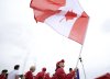 Canada flagbearer Maude Charron waves a national flag on her team's boat during the opening ceremony of the 2024 Summer Olympics on the Seine River in Paris, Friday, July 26, 2024. (Cao Can/Pool Photo via AP)