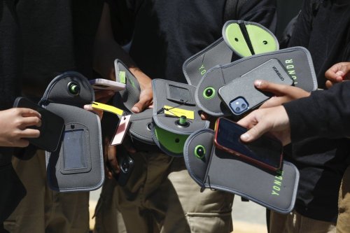 FILE - A student uses their cell phone after unlocking the pouch that secures it from use during the school day at Bayside Academy, Friday, Aug. 16, 2024, in San Mateo, Calif. (Lea Suzuki/San Francisco Chronicle via AP, File)
