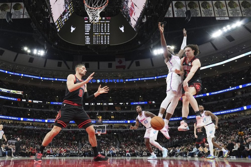 Chicago Bulls guard Josh Giddey, right, passes to center Nikola Vucevic, left, as Miami Heat center Bam Adebayo guards during the second half of an NBA basketball game in Chicago, Wednesday, April 9, 2025. (AP Photo/Nam Y. Huh)