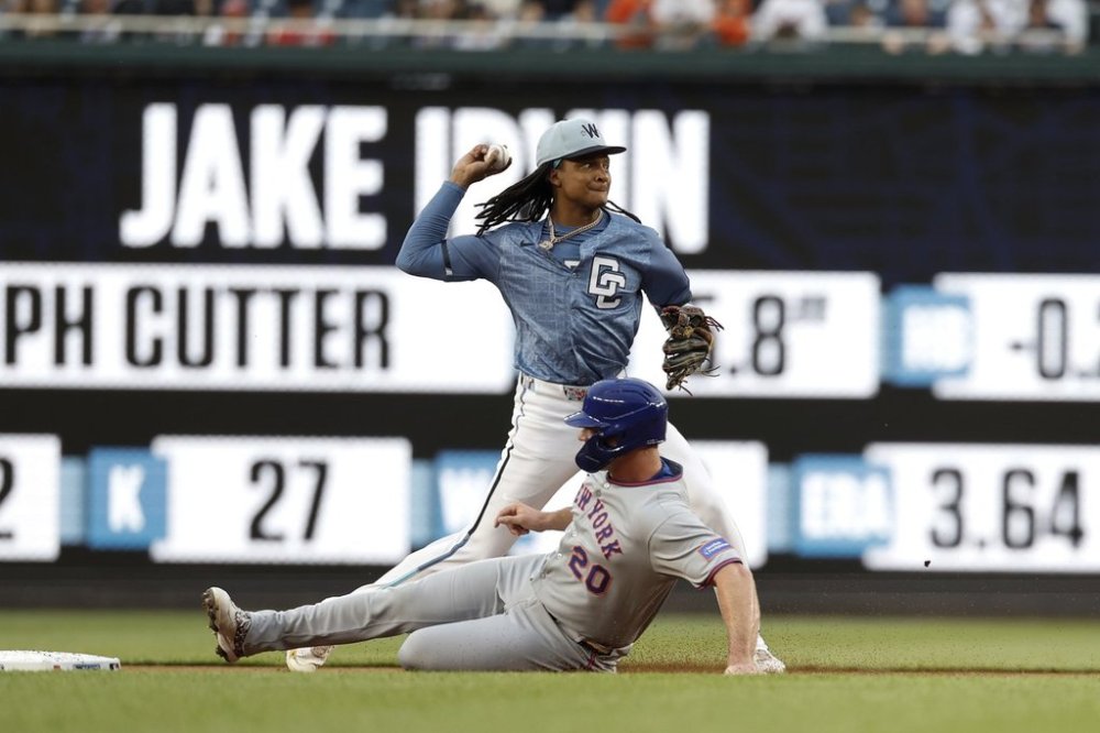 Washington Nationals shortstop CJ Abrams, top, gets a force out against New York Mets' Pete Alonso (20) and attempts to turn a double play on a ball hit by Brandon Nimmo during the first inning of a baseball game in Washington, Friday, April 25, 2025. (AP Photo/Terrance Williams)