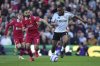 Fulham's Alex Iwobi, right, challenges for the ball with Liverpool's Mohamed Salah during the English Premier League soccer match between Fulham and Liverpool, at Craven Cottage, London, Sunday, April 6, 2025. (AP Photo/Kin Cheung)