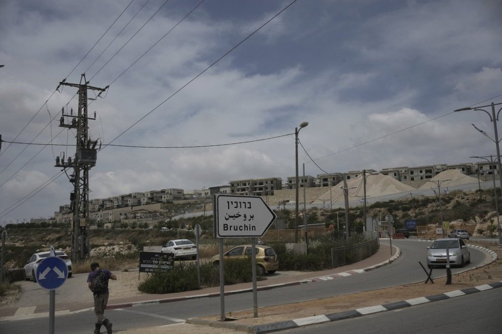 A young Israeli settler walks to a bus stop outside of the West Bank settlement of Bruchin on Thursday, May 15, 2025. (AP Photo/Maya Alleruzzo)