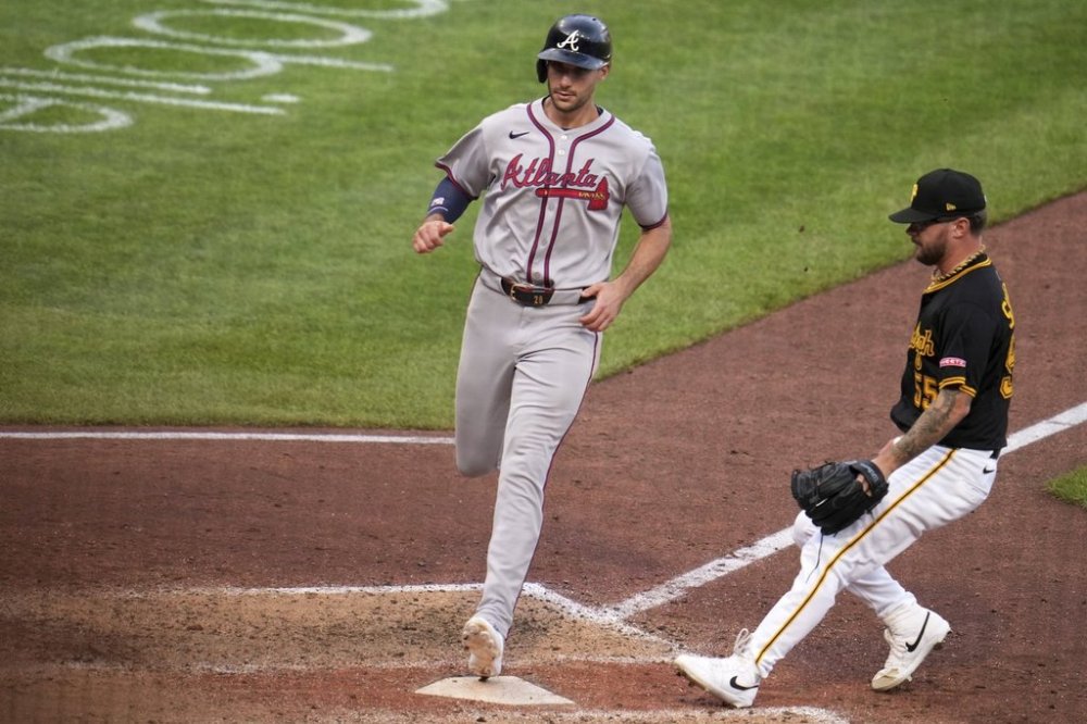 Atlanta Braves' Matt Olson, left, scores from third base on a wild pitch by Pittsburgh Pirates pitcher Chase Shugart, right, during the 11th inning of a baseball game in Pittsburgh, Saturday, May 10, 2025. (AP Photo/Gene J. Puskar)