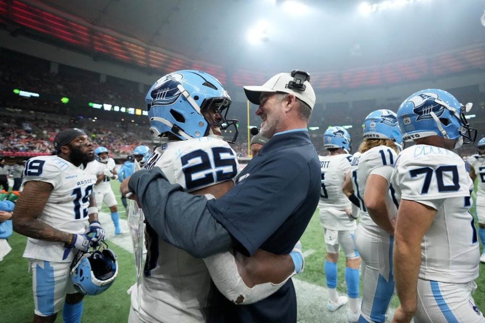 Toronto Argonauts head coach Ryan Dinwiddie, left, celebrates with teammate Ka'Deem Carey (25) during second half CFL football action at the 111th Grey Cup against the Winnipeg Blue Bombers, in Vancouver, B.C., Sunday, Nov. 17, 2024. THE CANADIAN PRESS/Nathan Denette